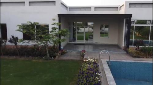 ラホールにあるLux Farm House with Swimming Poolの正面にプールがある家