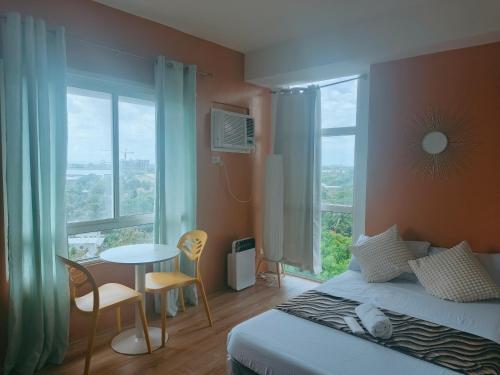 a bedroom with a bed and a table and windows at Mesavirre Garden Residences Condo Bacolod in Bacolod