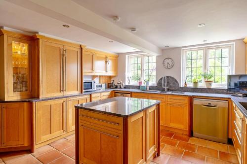 a large kitchen with wooden cabinets and a sink at Finest Retreats - The Old Rectory in Tring