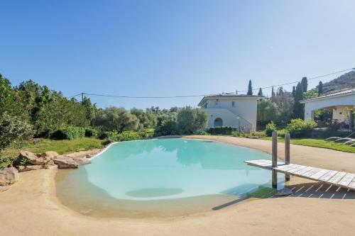 une grande piscine bleue avec un banc devant une maison dans l'établissement L'Alivi di Losari 7 - piscine naturelle et jacuzzi, à Belgodère
