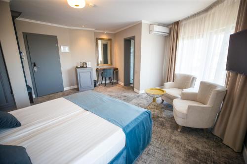 a hotel room with a bed and a couch and chairs at Hotel Meridian in Cluj-Napoca