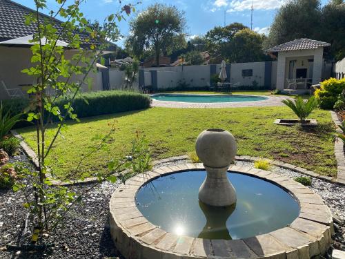 a small pond with a bird bath in a garden at Serene Guesthouse in Middelburg