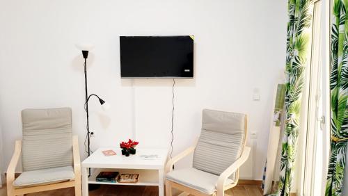 two chairs and a table with a tv on a wall at Karavaki apartments in Keri