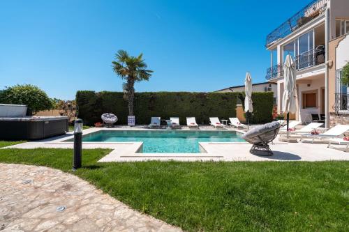 a swimming pool in a yard with chairs and a building at Evan by Briskva in Poreč