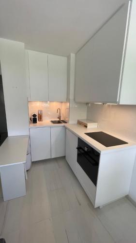 une cuisine blanche avec des armoires blanches et un évier dans l'établissement Studio Cannes Marina, à Mandelieu-la-Napoule