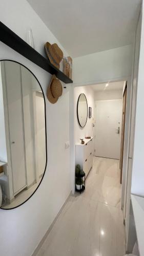 La salle de bains est pourvue d'un miroir et d'un mur blanc. dans l'établissement Studio Cannes Marina, à Mandelieu-la-Napoule