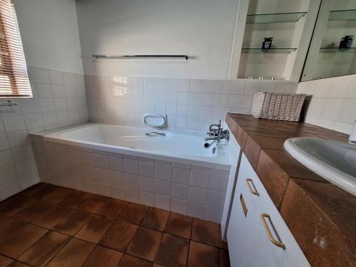 une salle de bain blanche avec une baignoire et un lavabo dans l'établissement Ocean Mooring Beach Apartments, à Port Alfred
