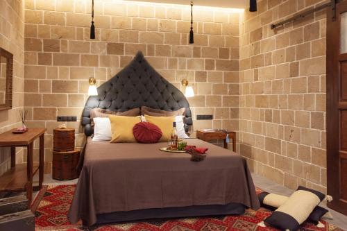 a bedroom with a large bed and a brick wall at Utopia Luxury Suites - Old Town in Rhodes Town