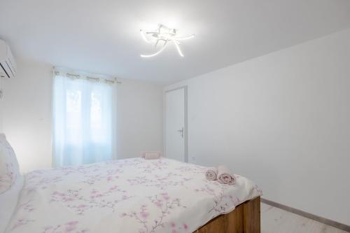 a white bedroom with a bed with a floral bedspread at Apartments and Rooms LEA in Bol