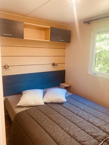a bedroom with a bed with a blue headboard at Mobil-home climatisé à 5 min de la mer, charmant in Camiers