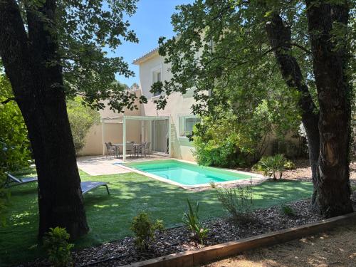 een zwembad in een tuin met bomen bij Les Jardins du Castelas - Domaine et Spas in Uchaux