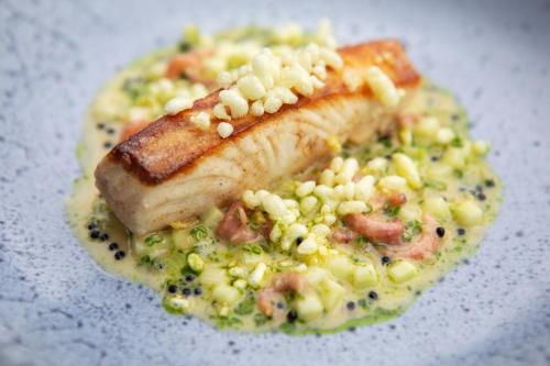 a plate of food with a piece of fish and peas at Blakeney House in Blakeney
