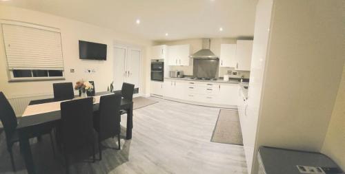 a white kitchen with a table and chairs in it at The Bergio Cosy Rooms in Northamtonshire
