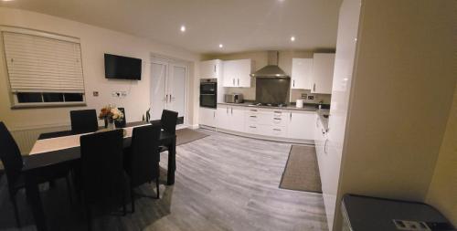 a kitchen with white cabinets and a table with chairs at The Bergio Cosy Rooms in Northamtonshire