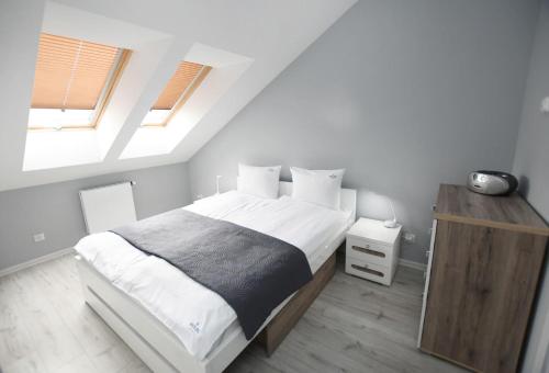 a bedroom with a large bed and two windows at Apartament Black Sunset Resort SurfingBird Grzybowo in Grzybowo