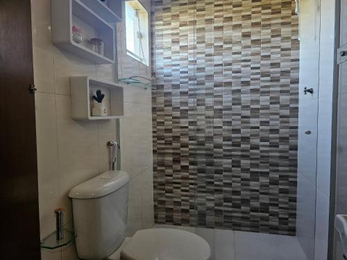 a bathroom with a toilet and a tiled wall at Acesso à Praia Ar Condicionado Conforto Garantido! in Saquarema
