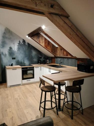 - une cuisine avec une table en bois et quelques tabourets dans l'établissement Appartement neuf Le Grenier d'Oscar, à La Bresse