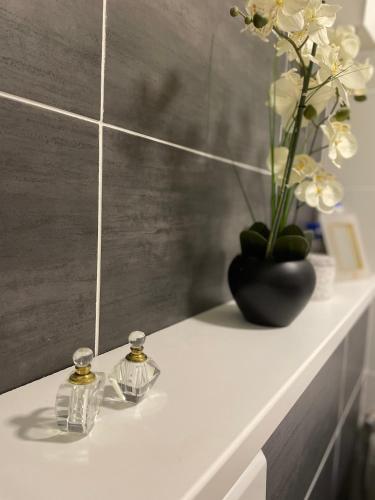 une étagère blanche avec deux flacons de parfum et un vase avec des fleurs dans l'établissement Studio-Champagne Lanson-Proche Hôpitaux-Universités-Parc Léo Lagrange, à Reims