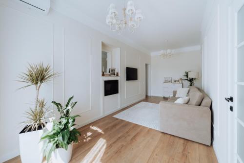 a white living room with a couch and a chandelier at Central 2BR on Petru Movilă Walk to It All in Chişinău