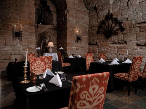 a dining room with tables and chairs and a brick wall at Dalhousie Castle Hotel in Bonnyrigg