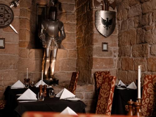 a table in a restaurant with a statue of a knight at Dalhousie Castle Hotel in Bonnyrigg