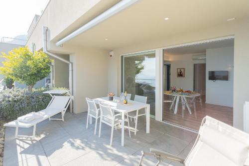 a patio with white chairs and a white table at Valarin Luxury Apartments & Wellness, Vercana by Rent All Como in Vercana