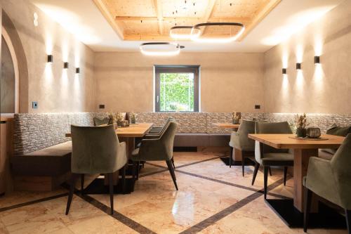 a restaurant with tables and chairs in a room at Hotel Burggräflerhof in Merano