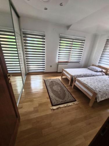 a bedroom with two beds and windows and a rug at Villa Center Sarajevo - FREE PARKING in Sarajevo