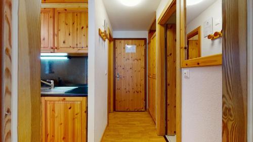 une petite cuisine avec des placards en bois et un couloir dans l'établissement Pracondu 2 402 - OUTDOOR & FUN charming apartment, à Nendaz