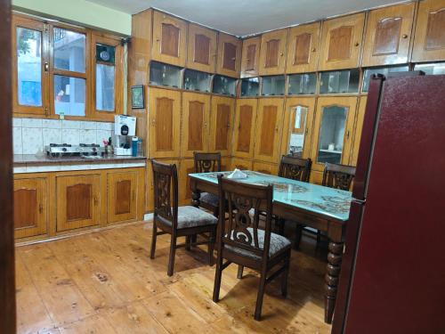 a kitchen with wooden cabinets and a table and chairs at The velox Traditional Home Stay in Kalpa