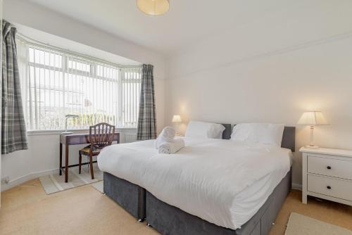 a bedroom with a large white bed and a desk at Livingstone Crescent - No 5 in St. Andrews