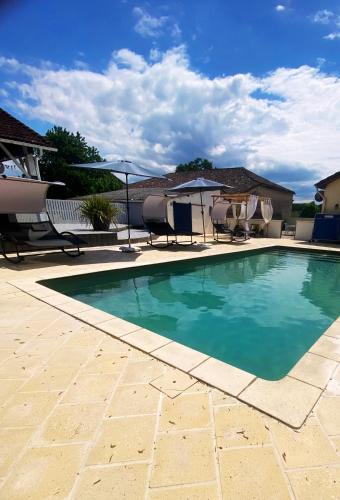 une piscine avec chaises et parasols sur un patio dans l'établissement Maison de Campagne 4 places, avec Piscine et Jacuzzi, à Savignac-sur-Leyze