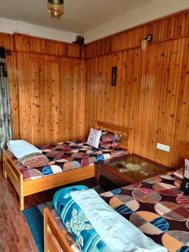 three beds in a room with wooden walls at Miryok Homes in Mirik
