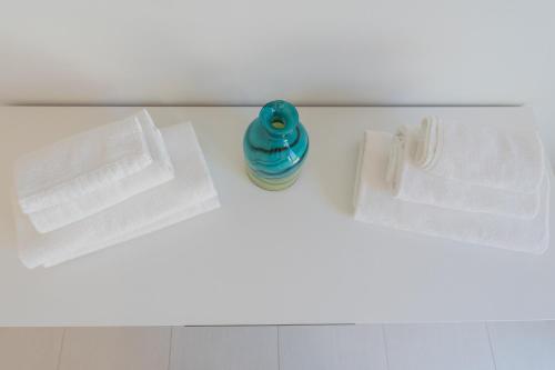 a bathroom counter with two white towels and a blue bottle at Valarin Luxury Apartments & Wellness, Vercana by Rent All Como in Vercana