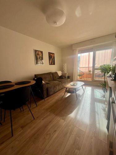 un salon avec un canapé et une table dans l'établissement Serenity, appt avec loggia à 5min de la plage, à Courseulles-sur-Mer