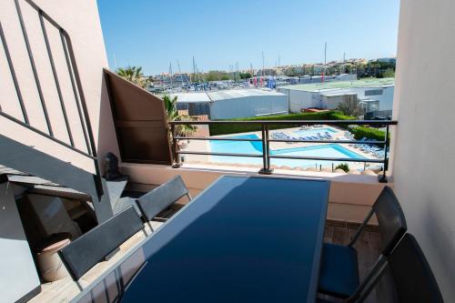 d'un balcon avec une table bleue, des chaises et une piscine. dans l'établissement Le Solarium, au Cap d'Agde