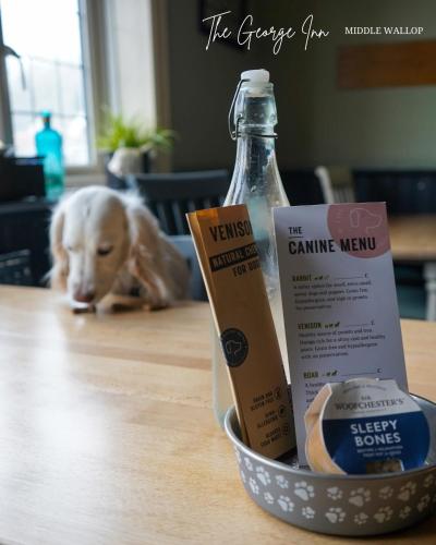 Un perro acostado en una mesa con una botella de leche. en The George Inn Middle Wallop, en Stockbridge