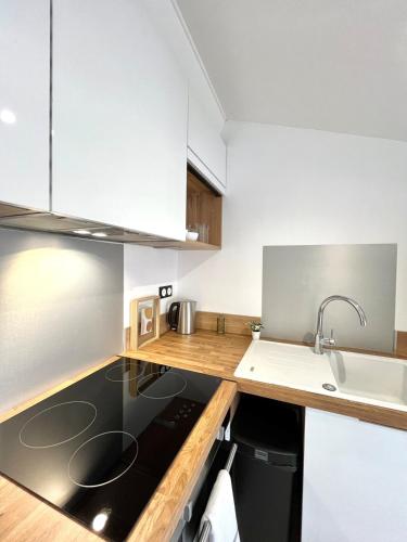 a kitchen with white cabinets and a sink at T3 rénové à 15 min de Lyon in Pierre-Bénite