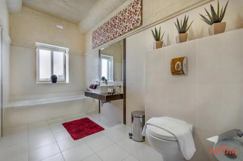 a bathroom with a toilet and a sink and a tub at Peaceful Farmhouse Retreat with Pool & Sun Lounger in Xagħra
