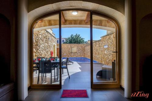 an open door to a patio with a table and chairs at Peaceful Farmhouse Retreat with Pool & Sun Lounger in Xagħra