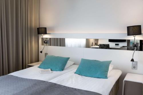 a bedroom with a white bed with two blue pillows at Scandic Julia in Turku