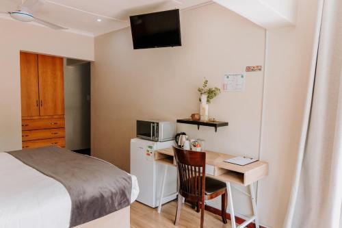 a small room with a desk and a bed at Serene Guesthouse in Middelburg