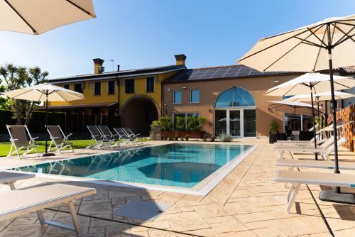a pool with chairs and umbrellas next to a building at Al Casale - Guest House in Sambruson