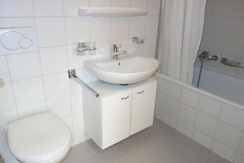 a white bathroom with a sink and a toilet at Pracondu 1 201 - OUTDOOR & FUN charming apartment in Nendaz