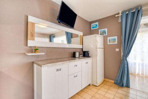 a kitchen with a white refrigerator and a tv at Les saules in Le Grau-dʼAgde