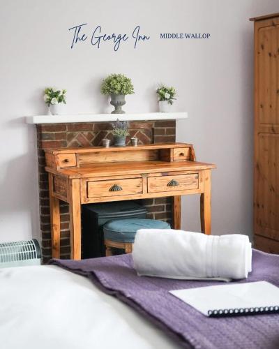 Un dormitorio con un escritorio de madera con chimenea. en The George Inn Middle Wallop, en Stockbridge