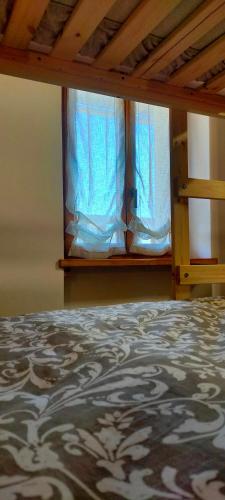 a bed in a room with a window with blue curtains at CA' DEL PITUR Apartments B&B Cicogna in Cicogna