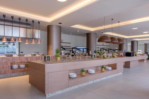 a restaurant with a counter with potted plants on it at Zeus Hotels Ydoria Resort in Adelianos Kampos