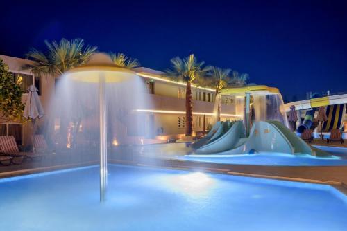 a swimming pool at night with a water slide at Zeus Hotels Ydoria Resort in Adelianos Kampos