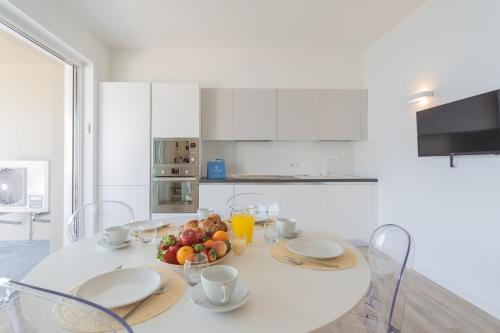 a white kitchen with a table with a bowl of fruit at Valarin Luxury Apartments & Wellness, Vercana by Rent All Como in Vercana